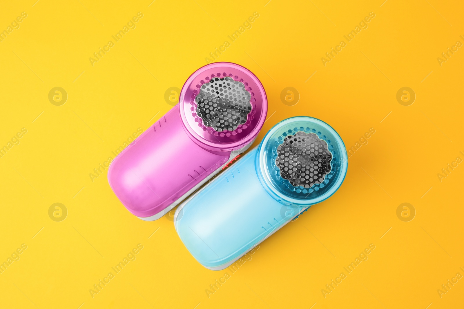 Photo of Modern fabric shavers on yellow background, flat lay