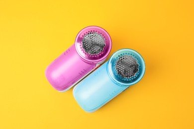 Modern fabric shavers on yellow background, flat lay