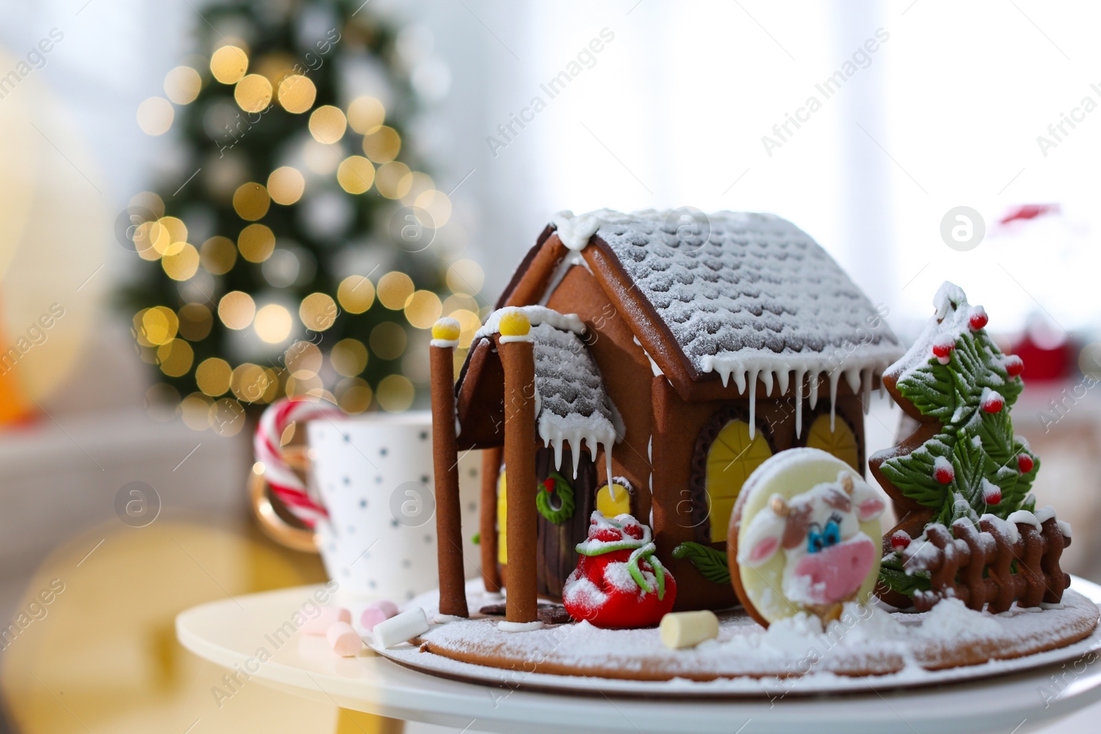 Photo of Beautiful gingerbread house decorated with icing on white table indoors, space for text