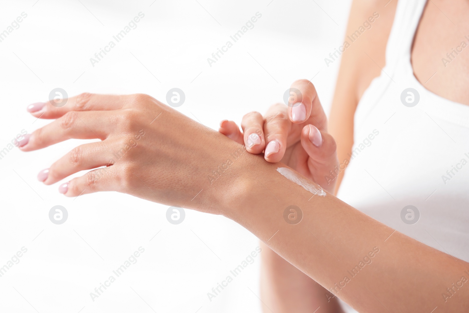 Photo of Young woman applying cream on white background, closeup. Beauty and body care