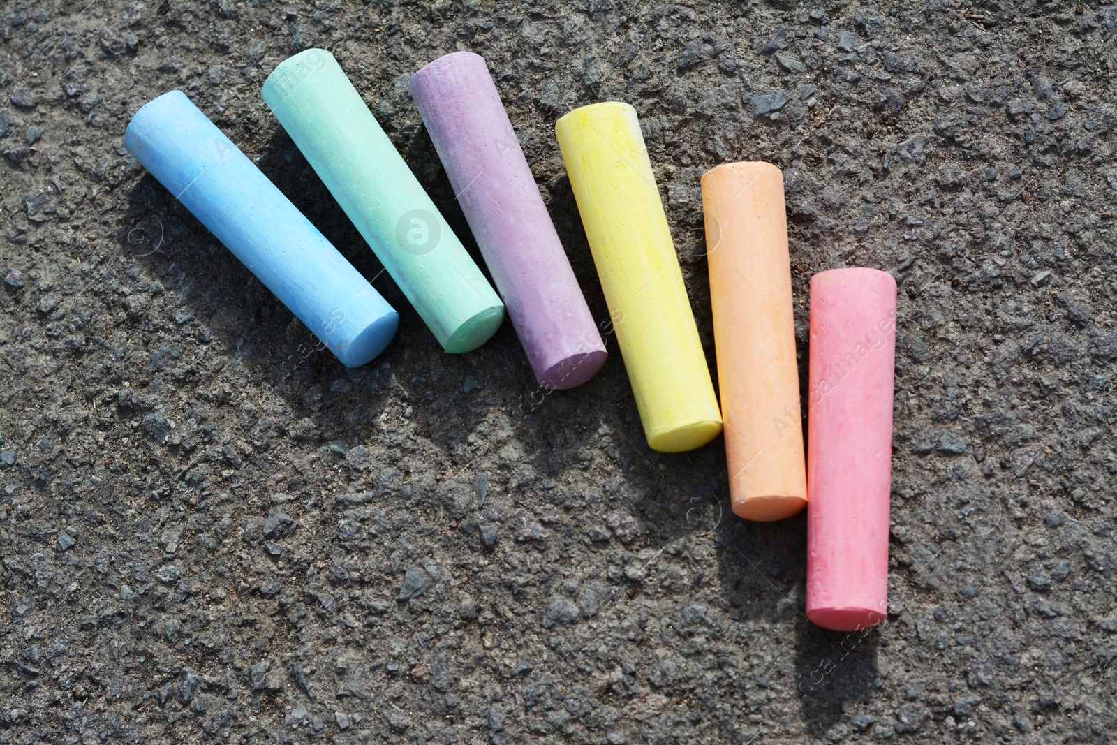 Photo of Colorful chalk sticks on asphalt, flat lay. Space for text