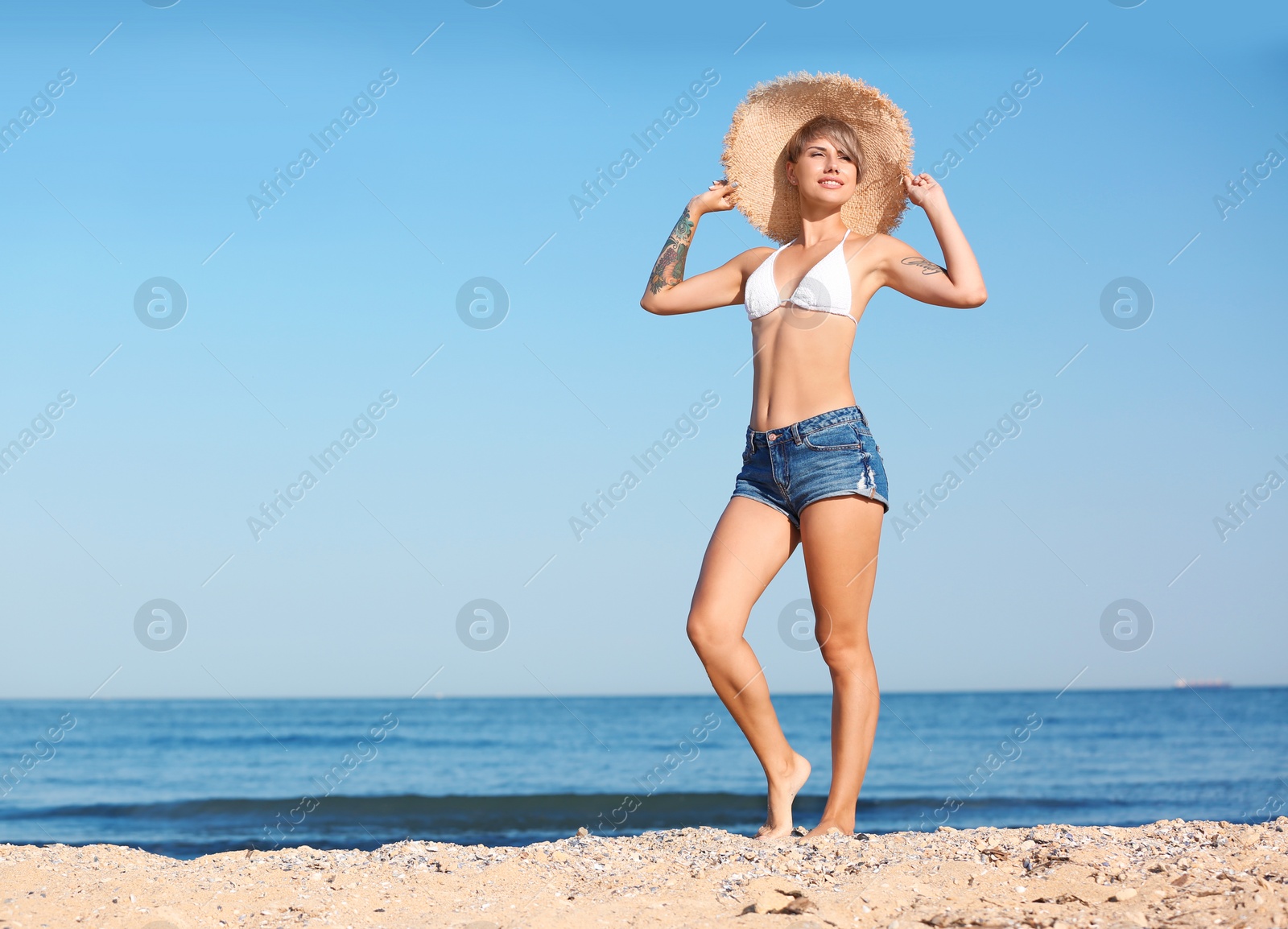 Photo of Young woman in straw hat on beach. Space for text