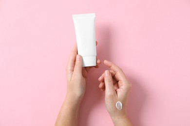 Photo of Woman with tube of hand cream on pink background, top view