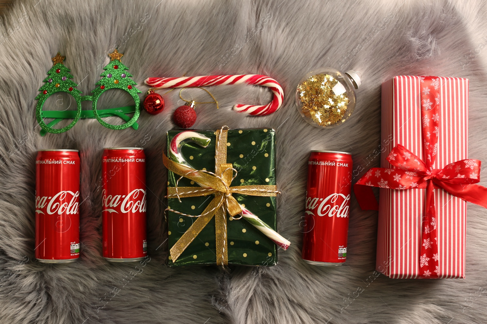 Photo of MYKOLAIV, UKRAINE - January 01, 2021: Flat lay composition with Coca-Cola cans and Christmas decorations on fur background