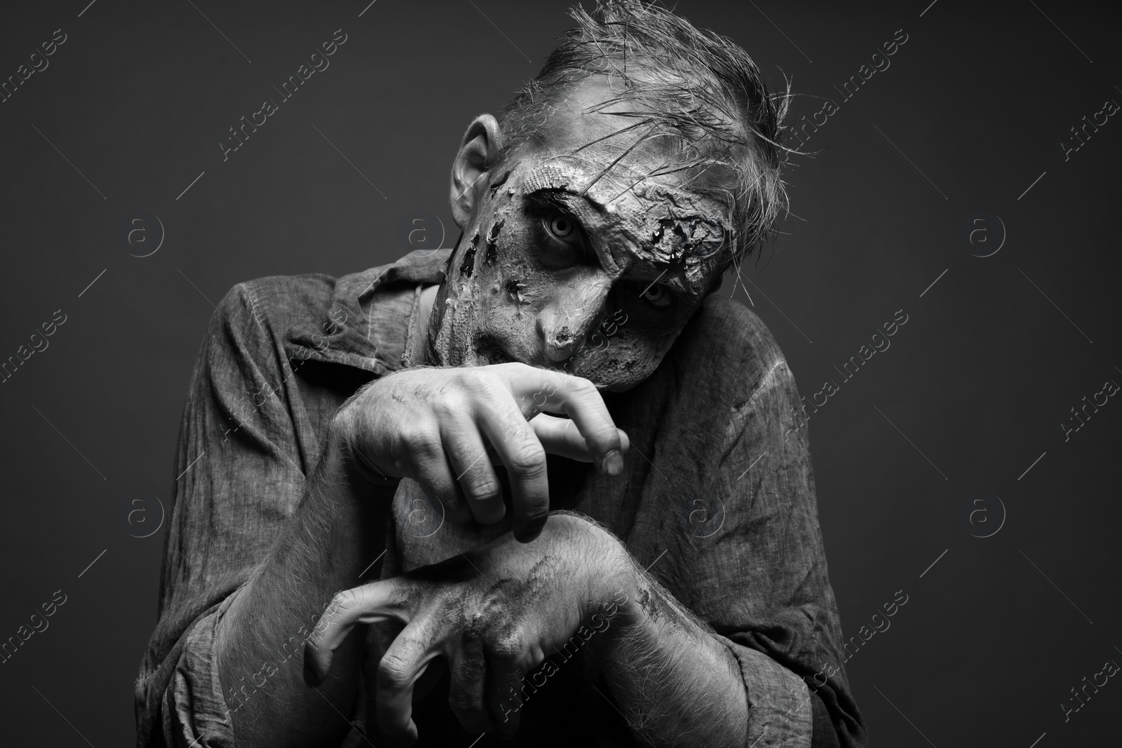 Photo of Scary zombie on dark background, black and white effect. Halloween monster