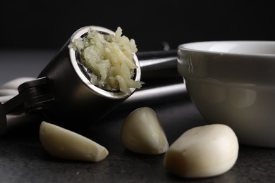 Photo of Garlic press, cloves and mince on grey table, closeup