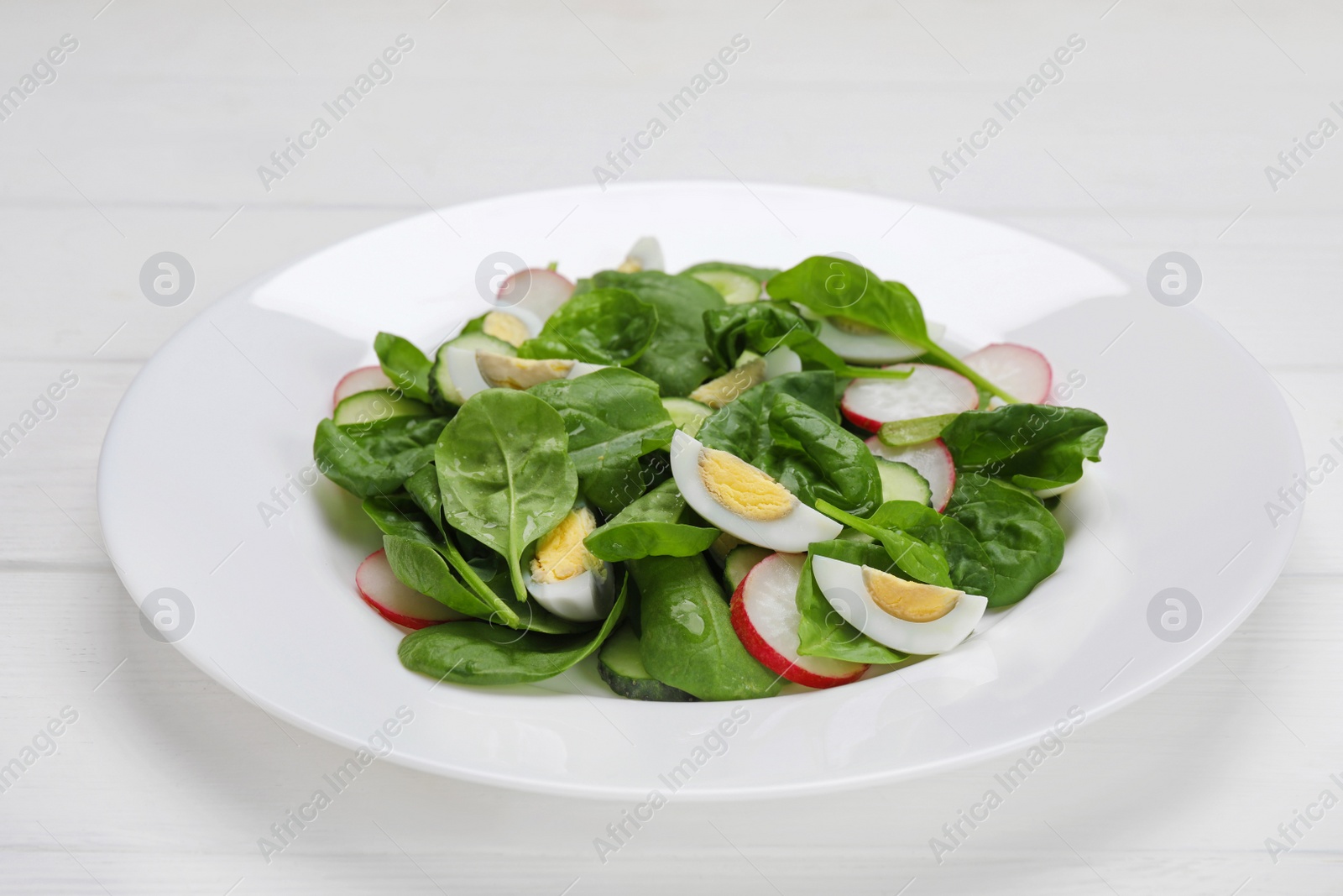 Photo of Delicious salad with boiled eggs, radish and spinach on white wooden table, closeup