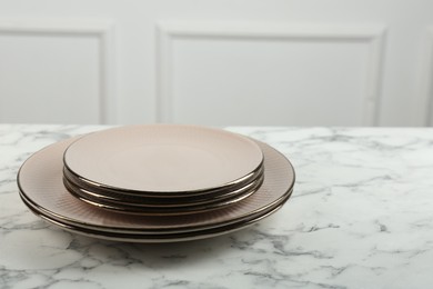 Photo of Beautiful ceramic plates on white marble table indoors, space for text