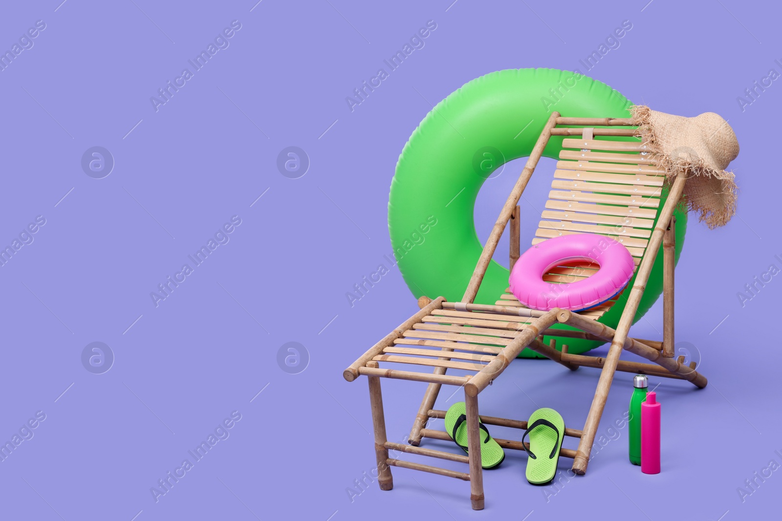 Photo of Deck chair, inflatable rings and other beach accessories on purple background, space for text. Summer vacation