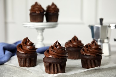 Photo of Delicious chocolate cupcakes with cream on grey table. Space for text