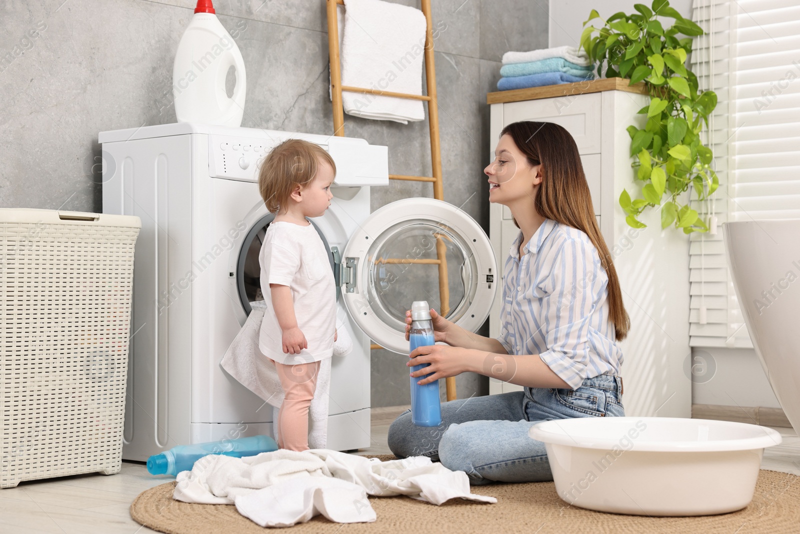Photo of Mother with her daughter washing baby clothes in bathroom