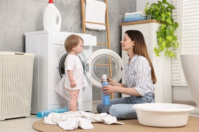 Mother with her daughter washing baby clothes in bathroom