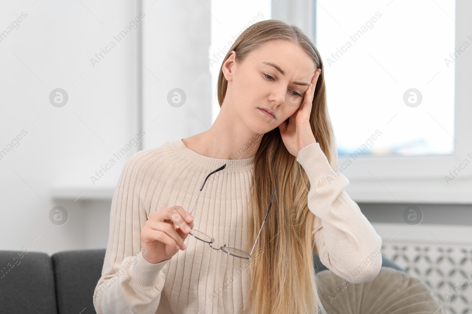 Photo of Overwhelmed young woman with glasses suffering from headache at home