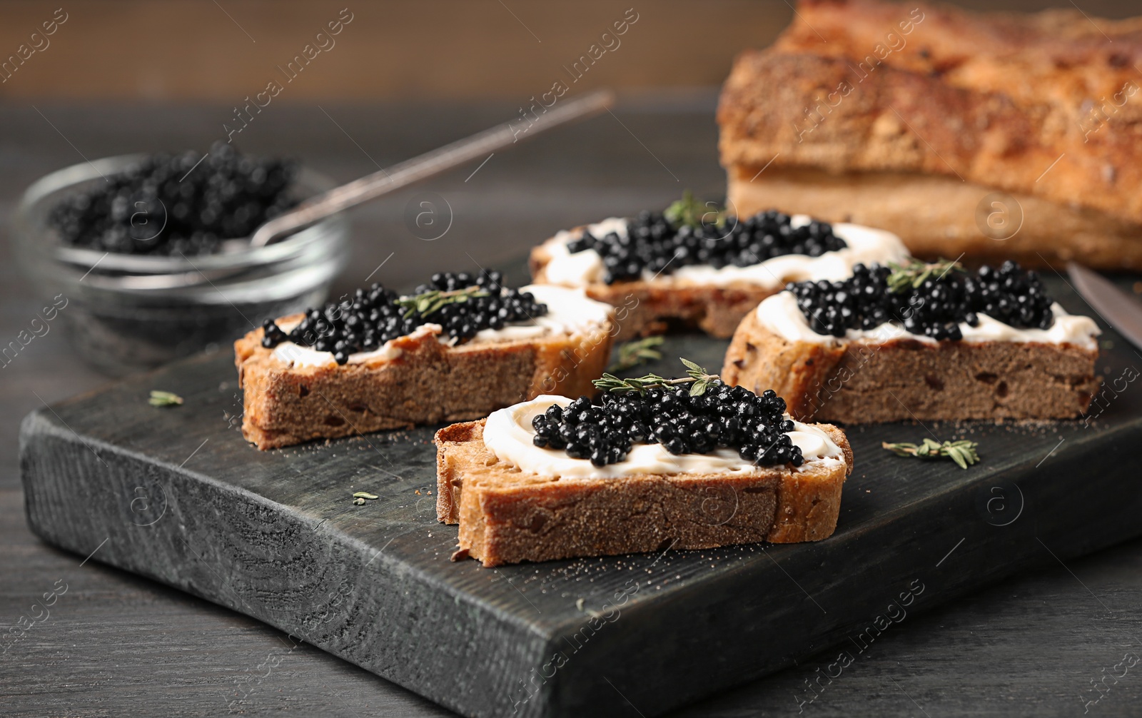 Photo of Sandwiches with black caviar and butter on wooden board