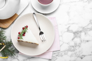 Photo of Slice of traditional Christmas cake decorated with rosemary and pomegranate seeds served on white marble table, flat lay. Space for text