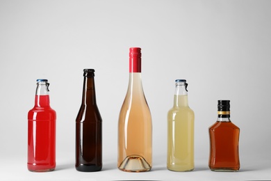 Photo of Bottles with different alcoholic drinks on light background