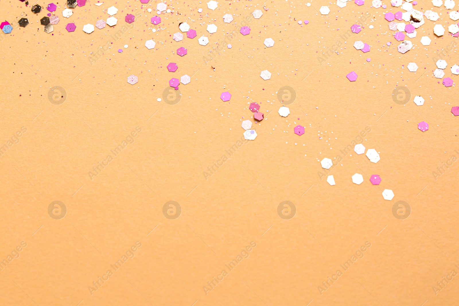 Photo of Shiny bright pink glitter on beige background. Space for text