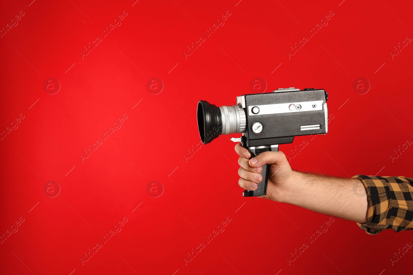 Photo of Man with vintage video camera on red background, closeup of hand. Space for text