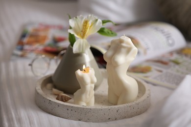 Photo of Beautiful body shaped candles and flower on bed indoors