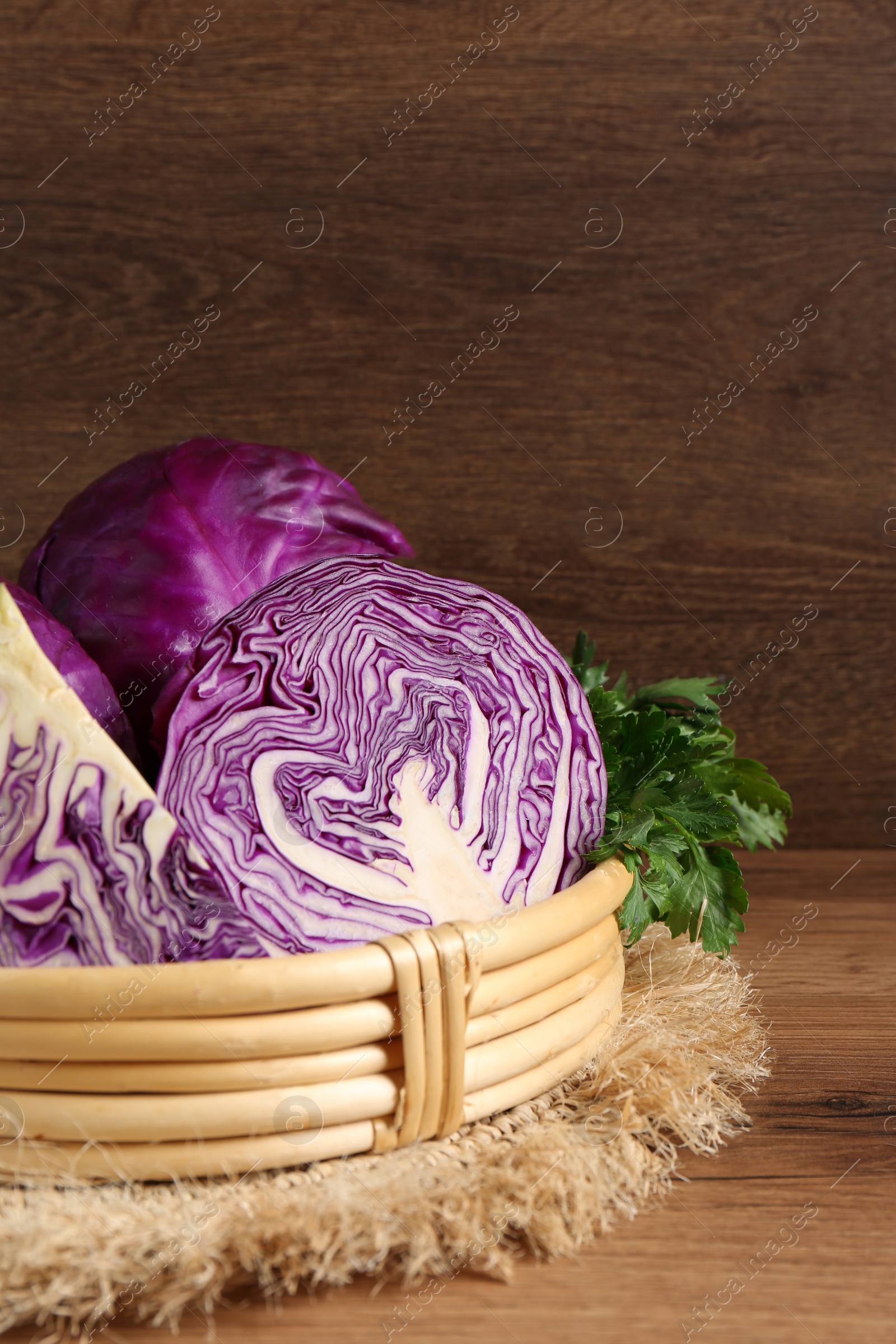 Photo of Wicker basket with fresh red cabbages on wooden table