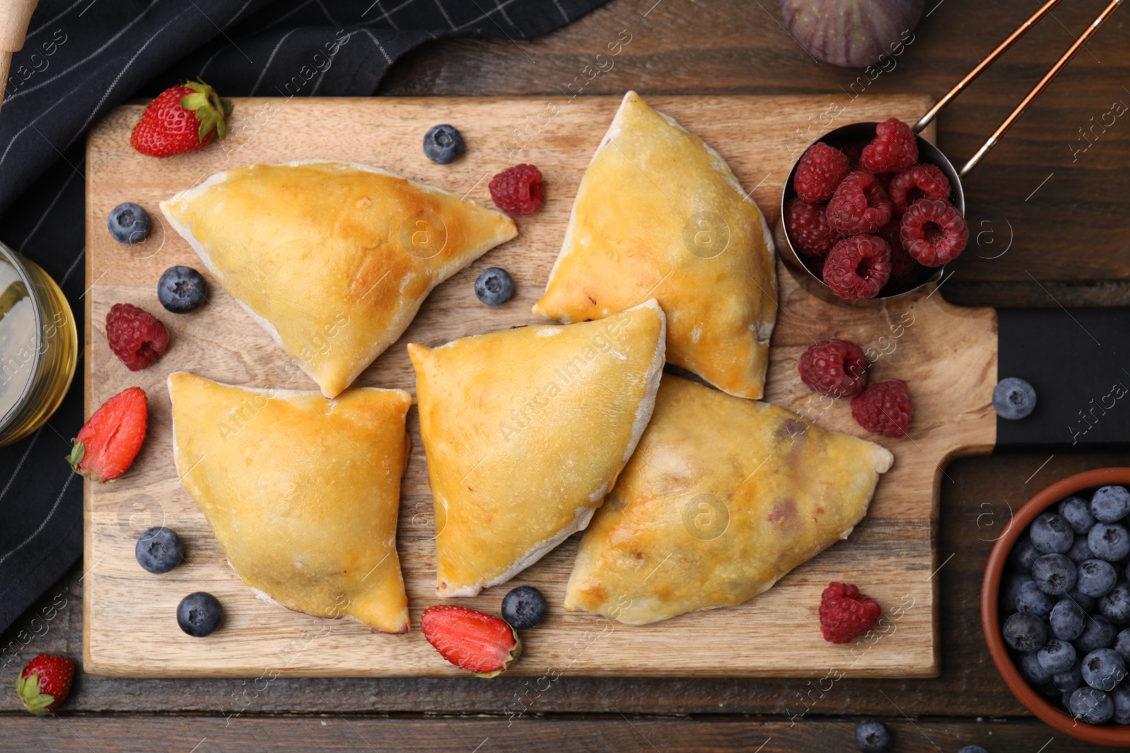 Photo of Delicious samosas and berries on wooden table, flat lay