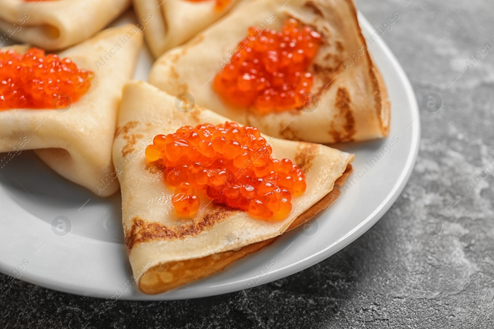 Photo of Thin pancakes with delicious red caviar on table