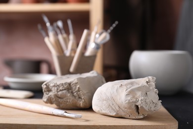 Clay and set of modeling tools on table in workshop, closeup