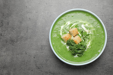 Photo of Tasty kale soup with croutons on grey table, top view. Space for text