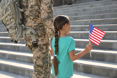 Photo of Soldier and his little daughter with American flag outdoors. Veterans Day in USA