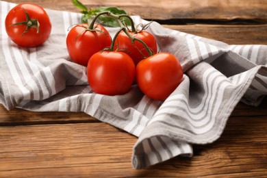 Photo of Kitchen towel and fresh tomatoes on wooden table