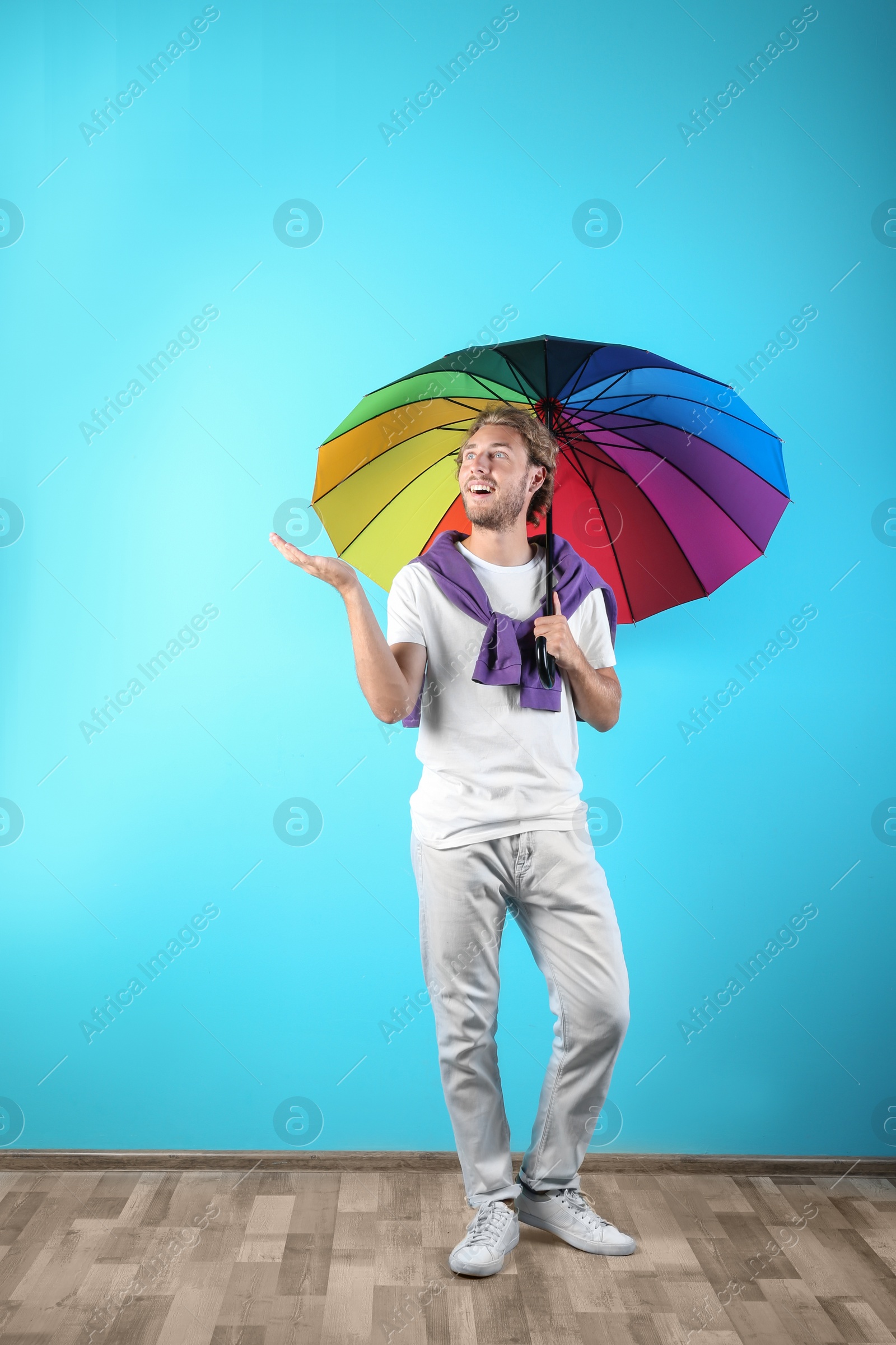 Photo of Man with rainbow umbrella near color wall