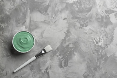 Photo of Spirulina facial mask and brush on grey table, flat lay. Space for text
