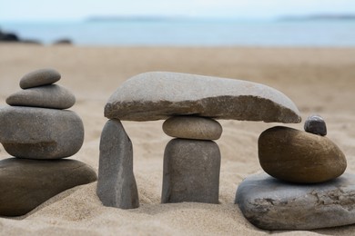 Stacks of stones on beautiful sandy beach near sea, closeup