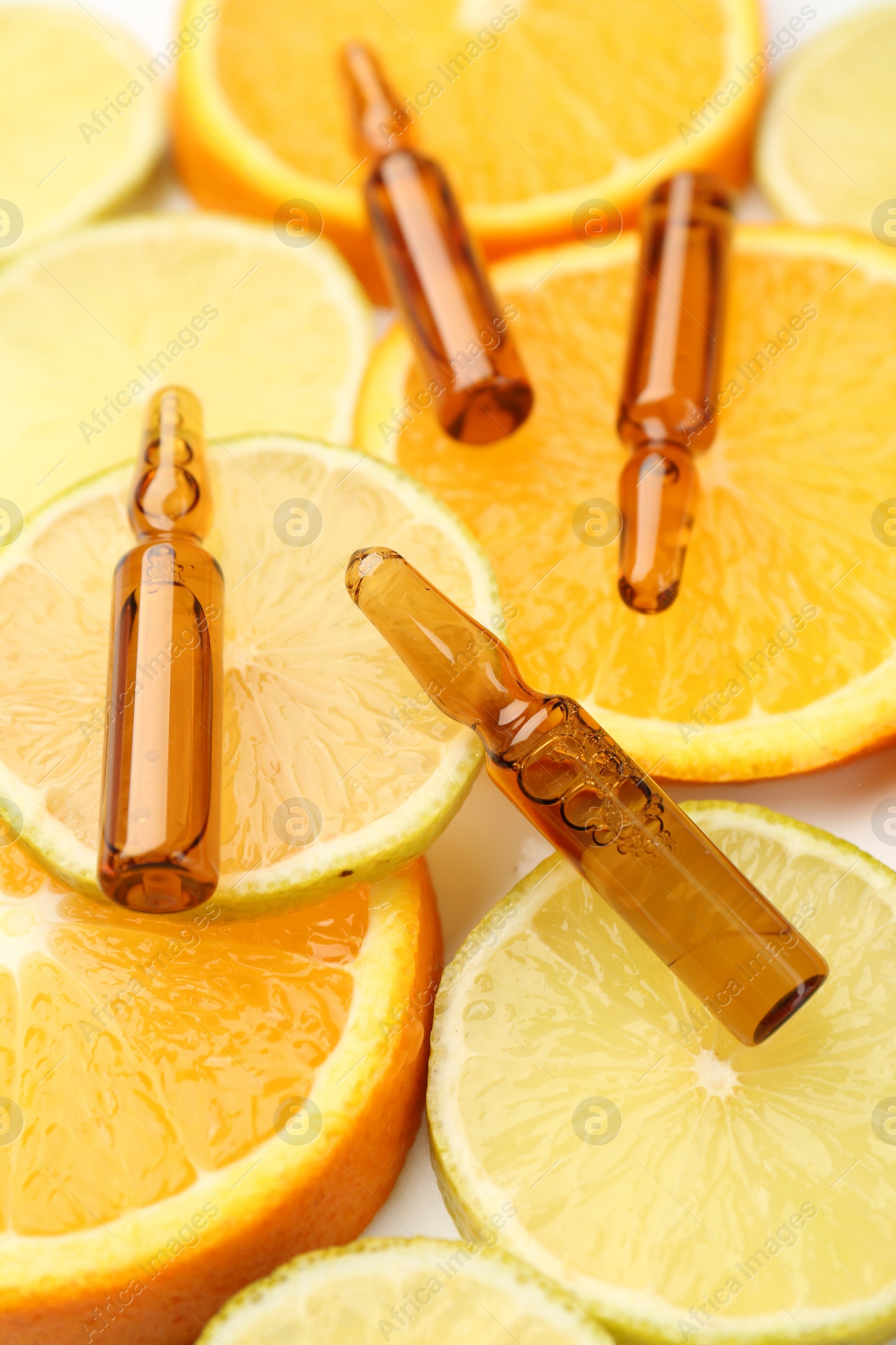 Photo of Skincare ampoules with vitamin C, lemon and orange slices on white background, closeup