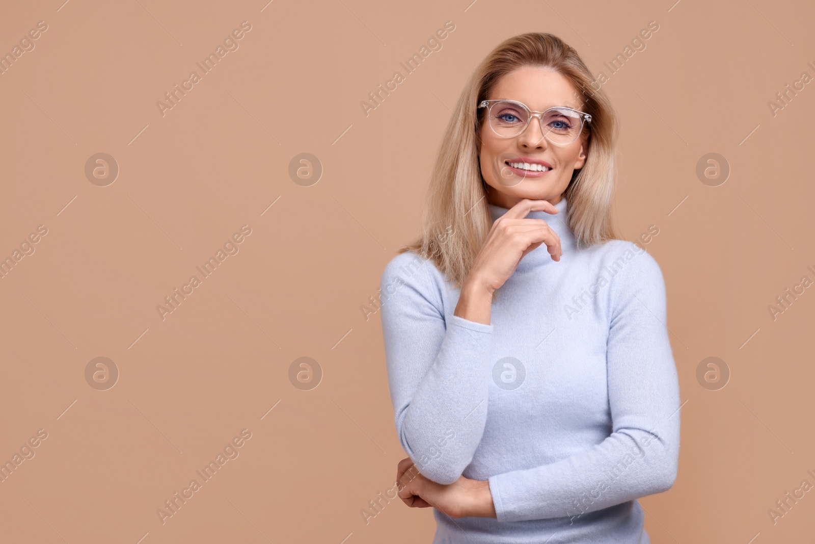 Photo of Portrait of smiling middle aged woman in glasses on beige background. Space for text