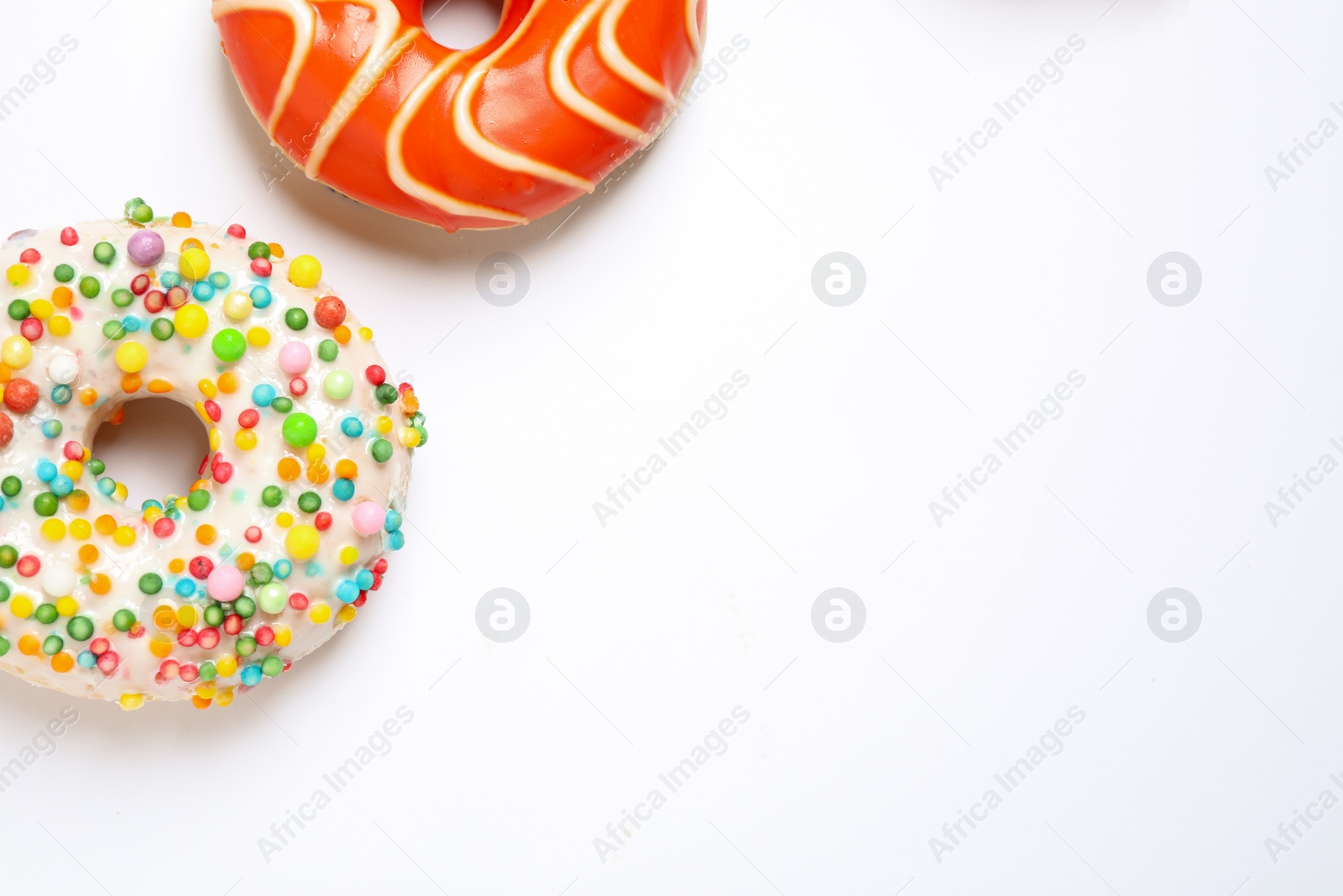 Photo of Delicious glazed donuts on white background, flat lay. Space for text