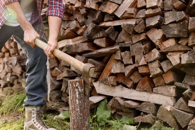 Man chopping wood near log pile outdoors, closeup