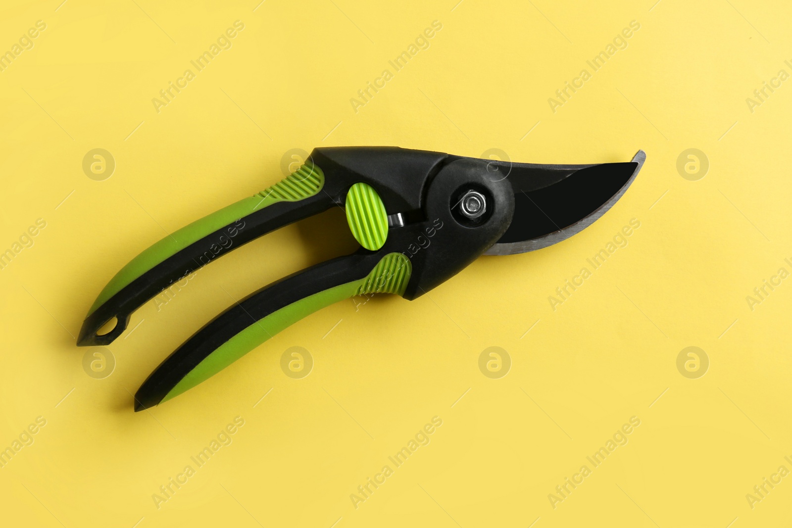 Photo of Secateur on light yellow background, top view