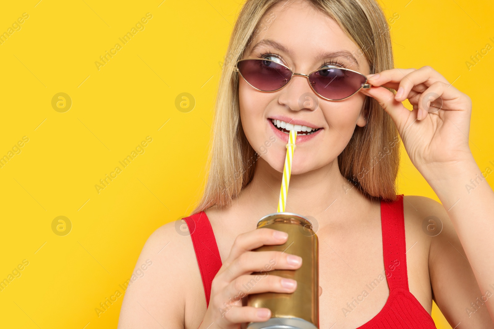 Photo of Beautiful happy woman drinking from beverage can on yellow background. Space for text