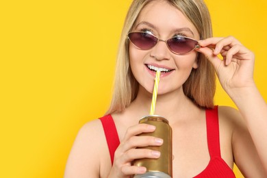 Photo of Beautiful happy woman drinking from beverage can on yellow background. Space for text