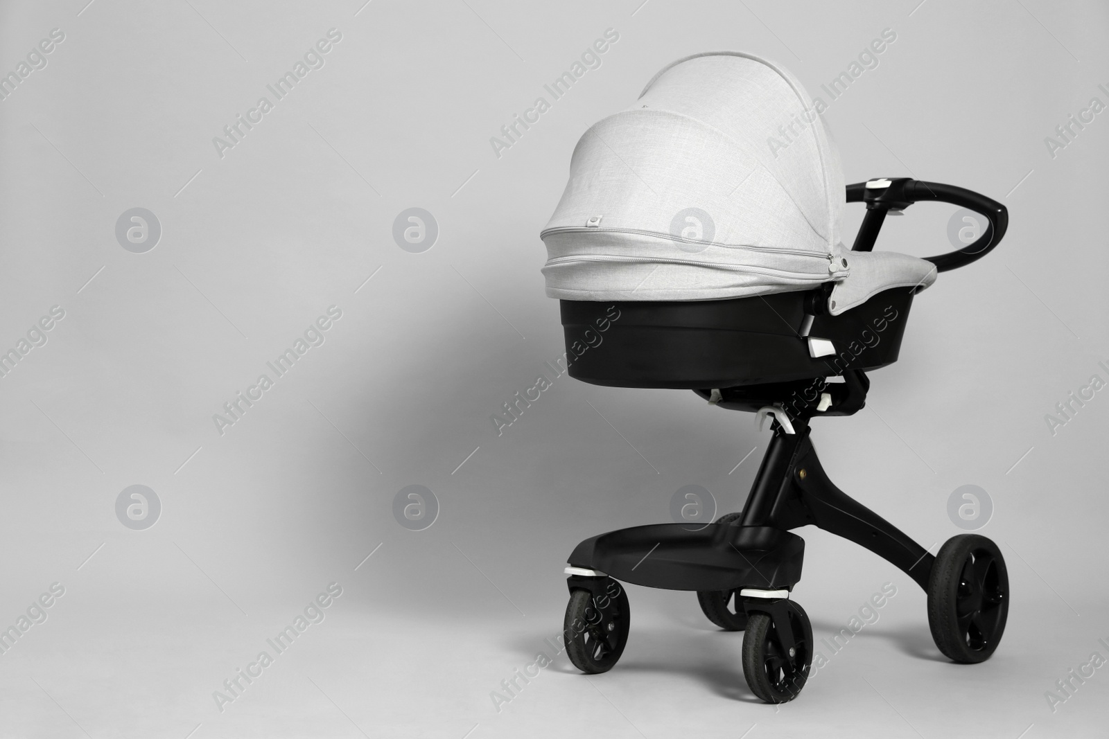 Photo of Baby carriage. Modern pram on grey background, space for text