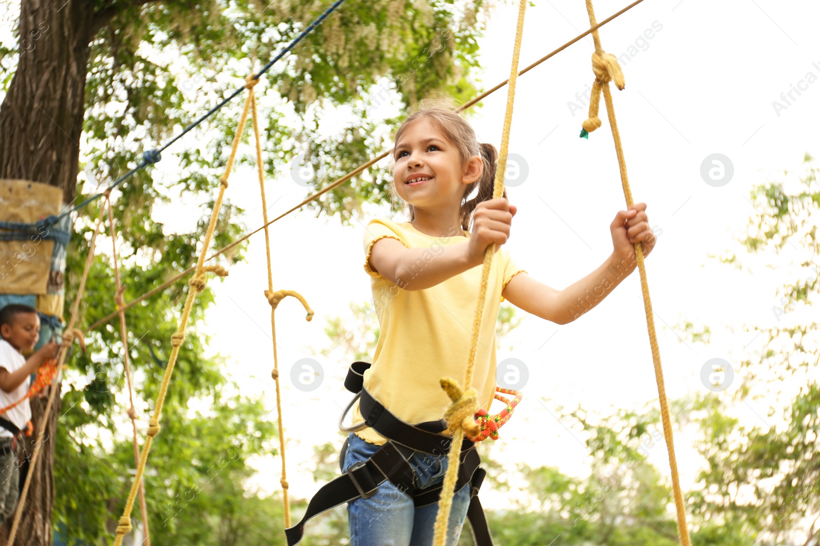 Photo of Little girl climbing in adventure park. Summer camp