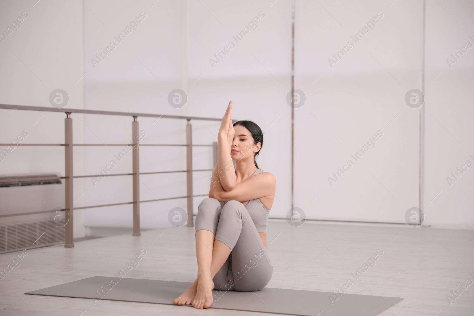 Photo of Young woman practicing eagle asana in yoga studio. Garudasana pose