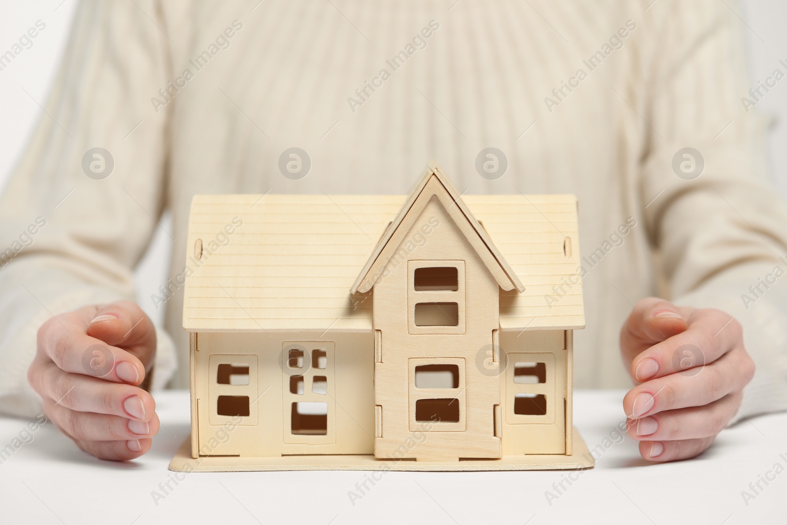 Photo of Home security concept. Woman with house model at white table, closeup