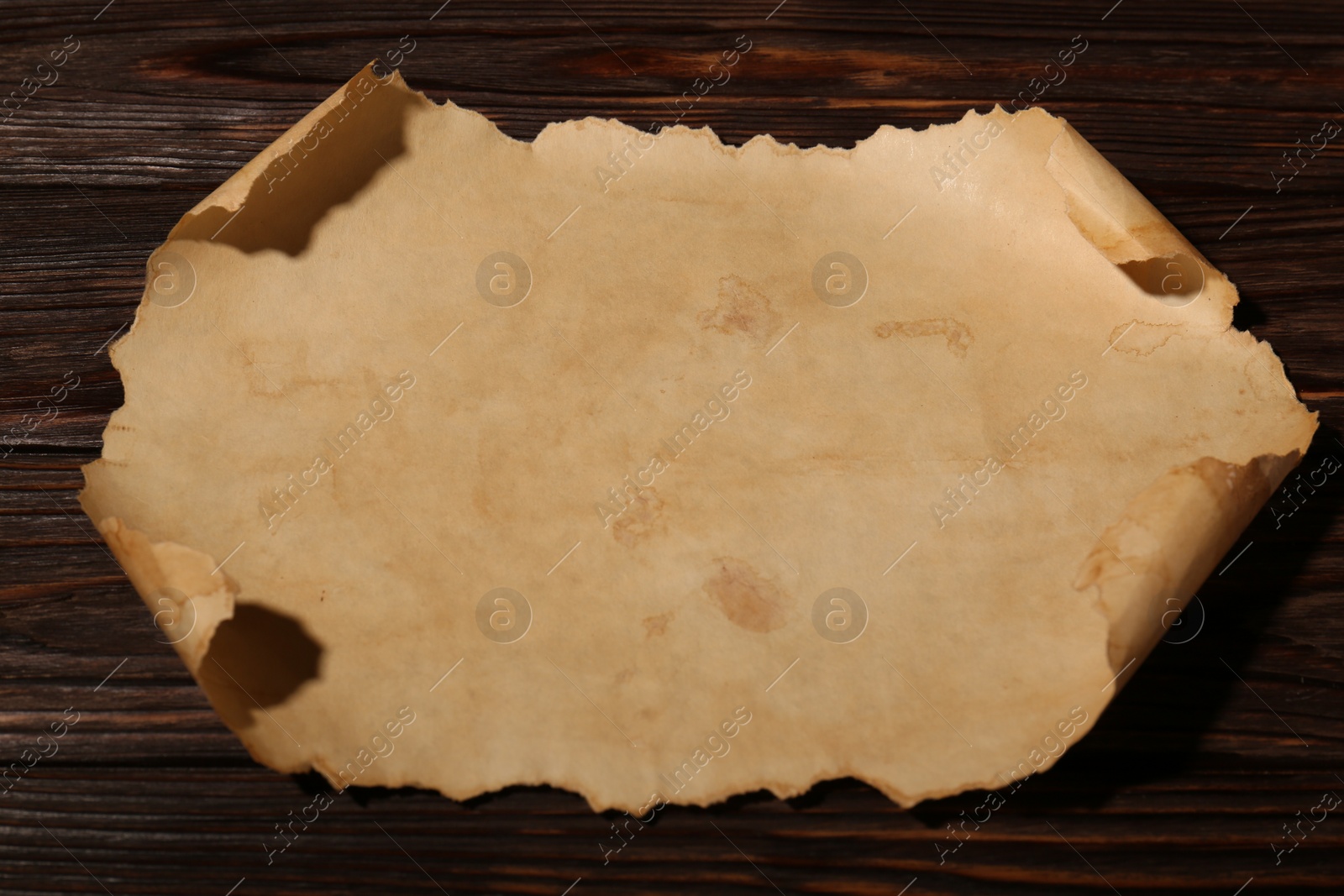 Photo of Sheet of old parchment paper on wooden table, above view
