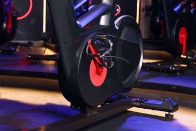 Photo of Modern exercise bike in fitness club, closeup. Indoor cycling class