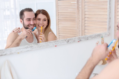 Photo of Young couple brushing teeth together in bathroom