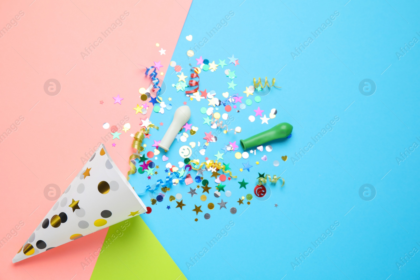 Photo of Bright confetti with party cracker on color background, flat lay