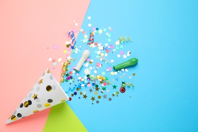 Bright confetti with party cracker on color background, flat lay