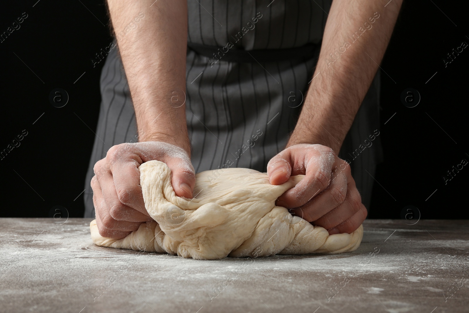 Photo of Male baker preparing bread dough at table, closeup